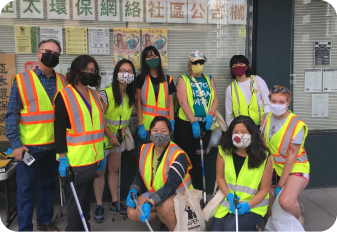 Nine APEN volunteers in volunteer gear and holding garbage bags and trash picker
