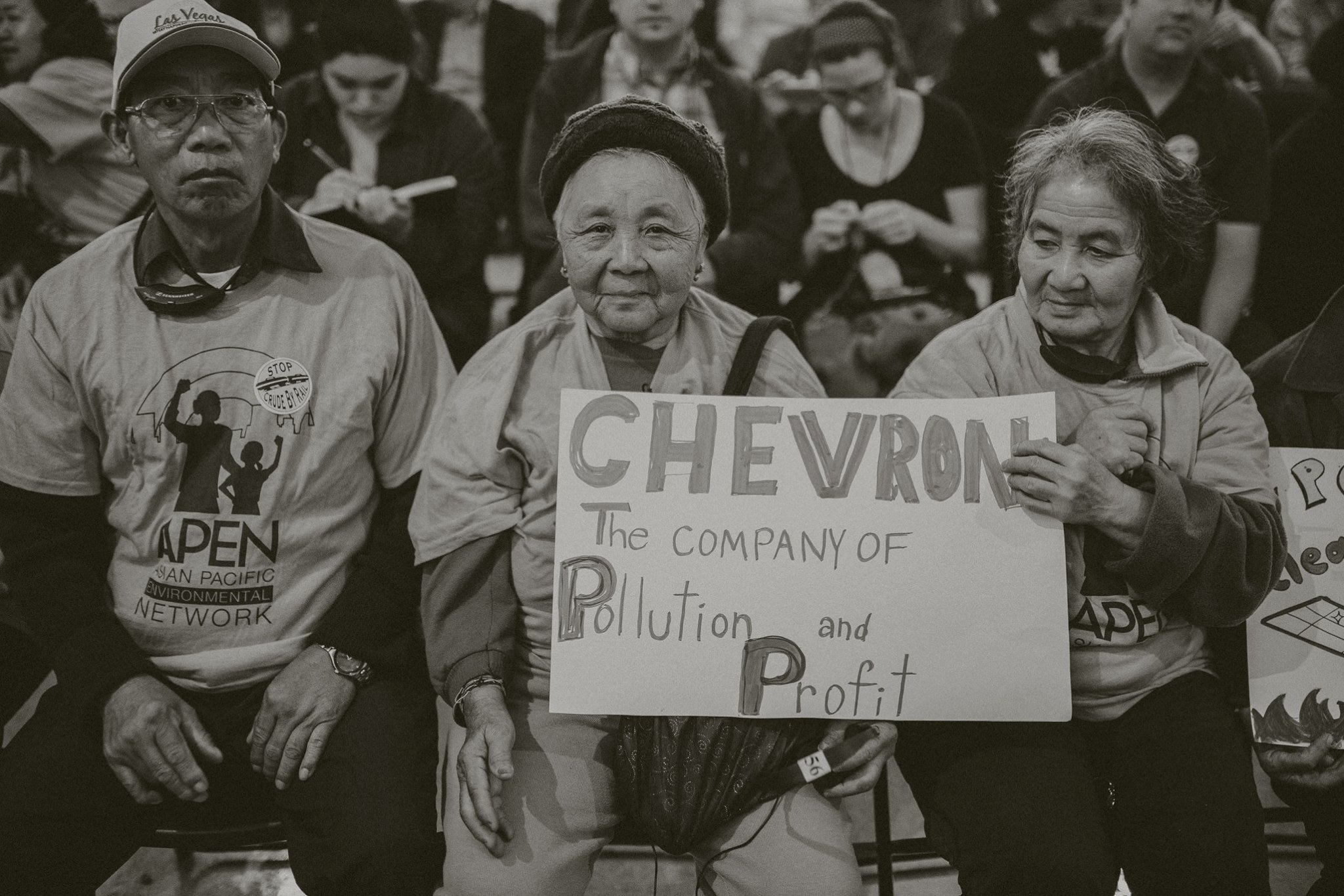 APEN Members hold a sign saying "Chevron, company of pollution and profit"