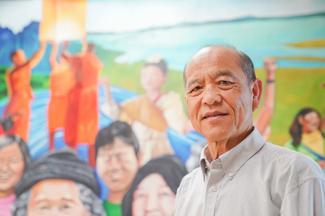Manh stands in front of the completed mural in the APEN office.