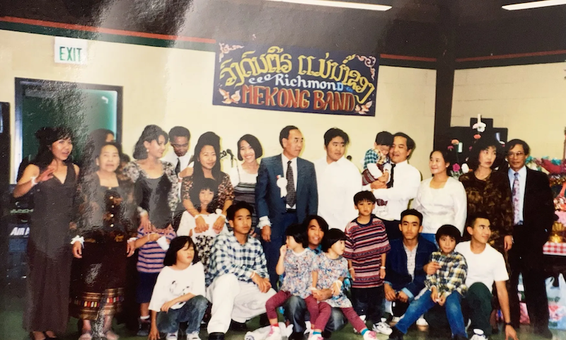 Chanh and Manh’s family pose together for a photograph in Richmond, California. Chanh stands second to top right; her brother Manh stands closer to center, holding his son.