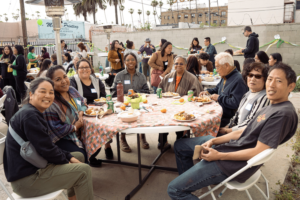 A group of people are smiling and eating at a table
