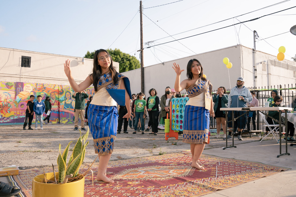 Two teenagers in traditional Laotian dress perform a dance