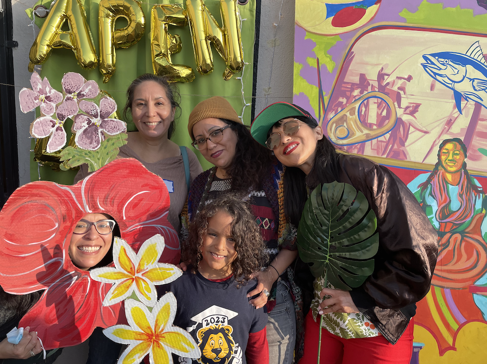 A group of people pose in front of the camera using props at a photobooth.